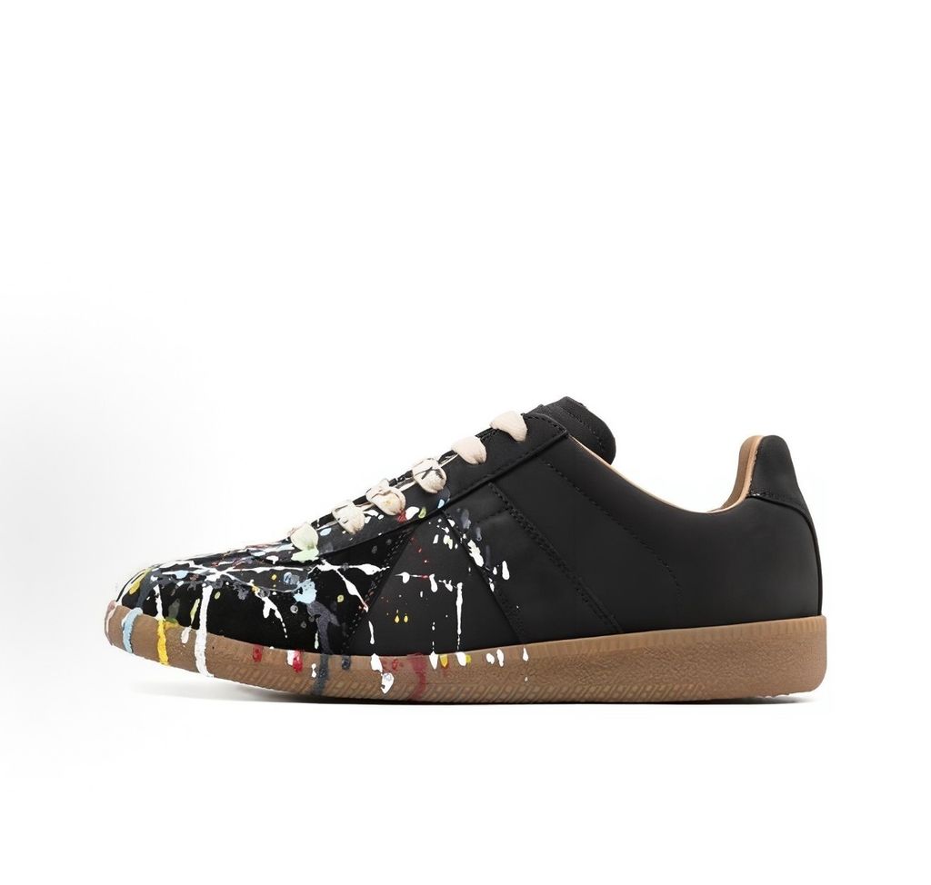 Maison Margiela Replica low-top sneaker in matte black calfskin leather featuring an avant-garde multicolor hand-splattered paint drop design across the toe box and a classic gum sole, style code S58WS0109P1895T1016.