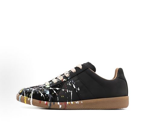 Maison Margiela Replica low-top sneaker in matte black calfskin leather featuring an avant-garde multicolor hand-splattered paint drop design across the toe box and a classic gum sole, style code S58WS0109P1895T1016.