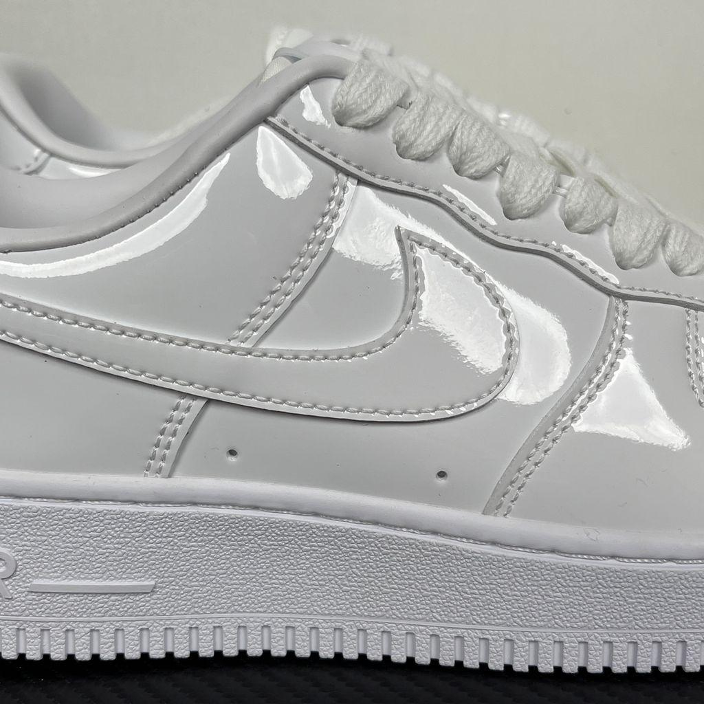 Nike Air Force 1 Low '07 Premium sneaker in high-gloss White Patent leather, featuring a tonal white Swoosh and classic chunky rubber sole, SKU IV2857-100.