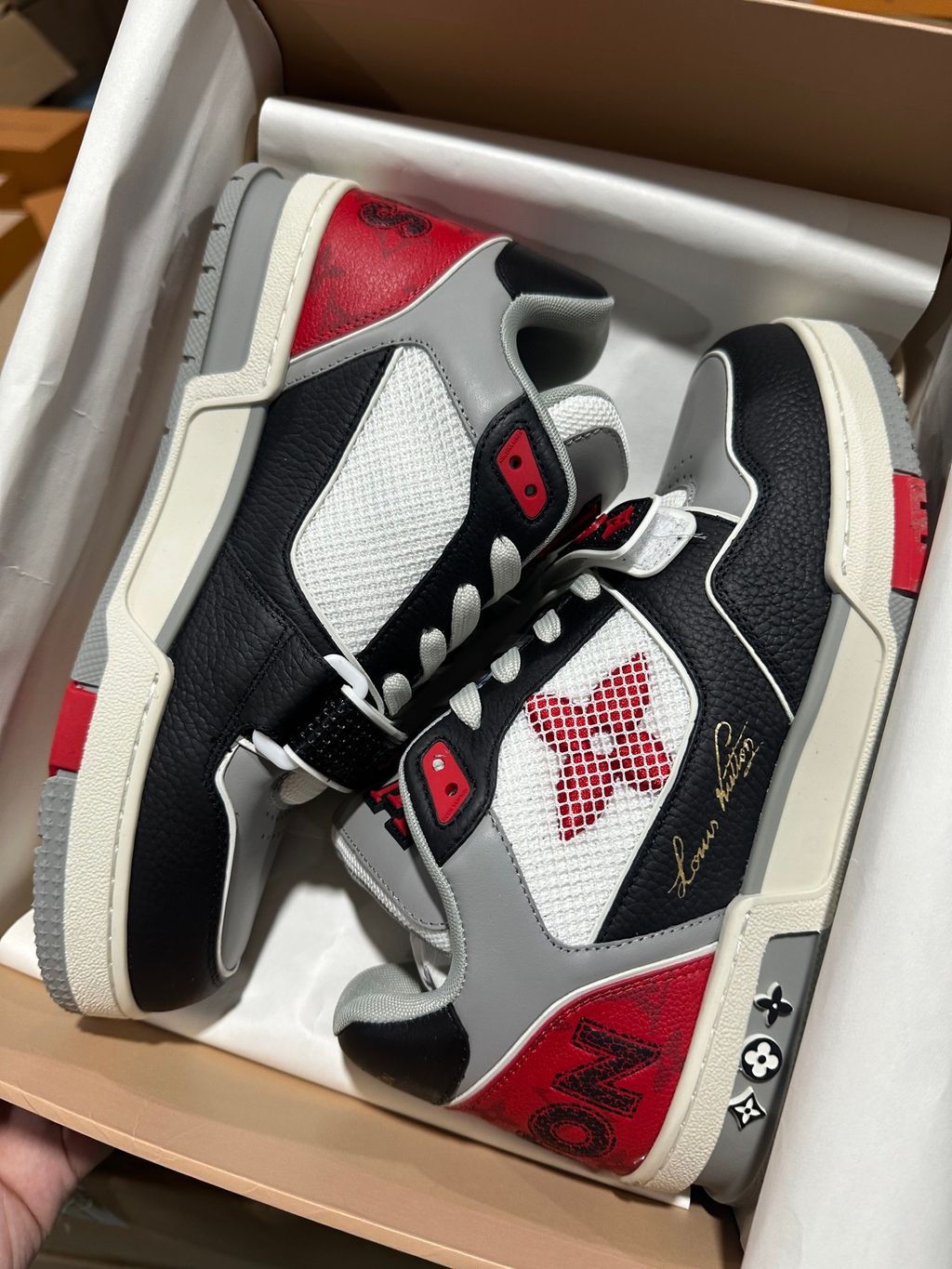 Louis Vuitton LV Trainer Mid sneaker in black, grey, and red premium calf leather, featuring a branded velcro strap across the forefoot, SKU 1AC4ZU.