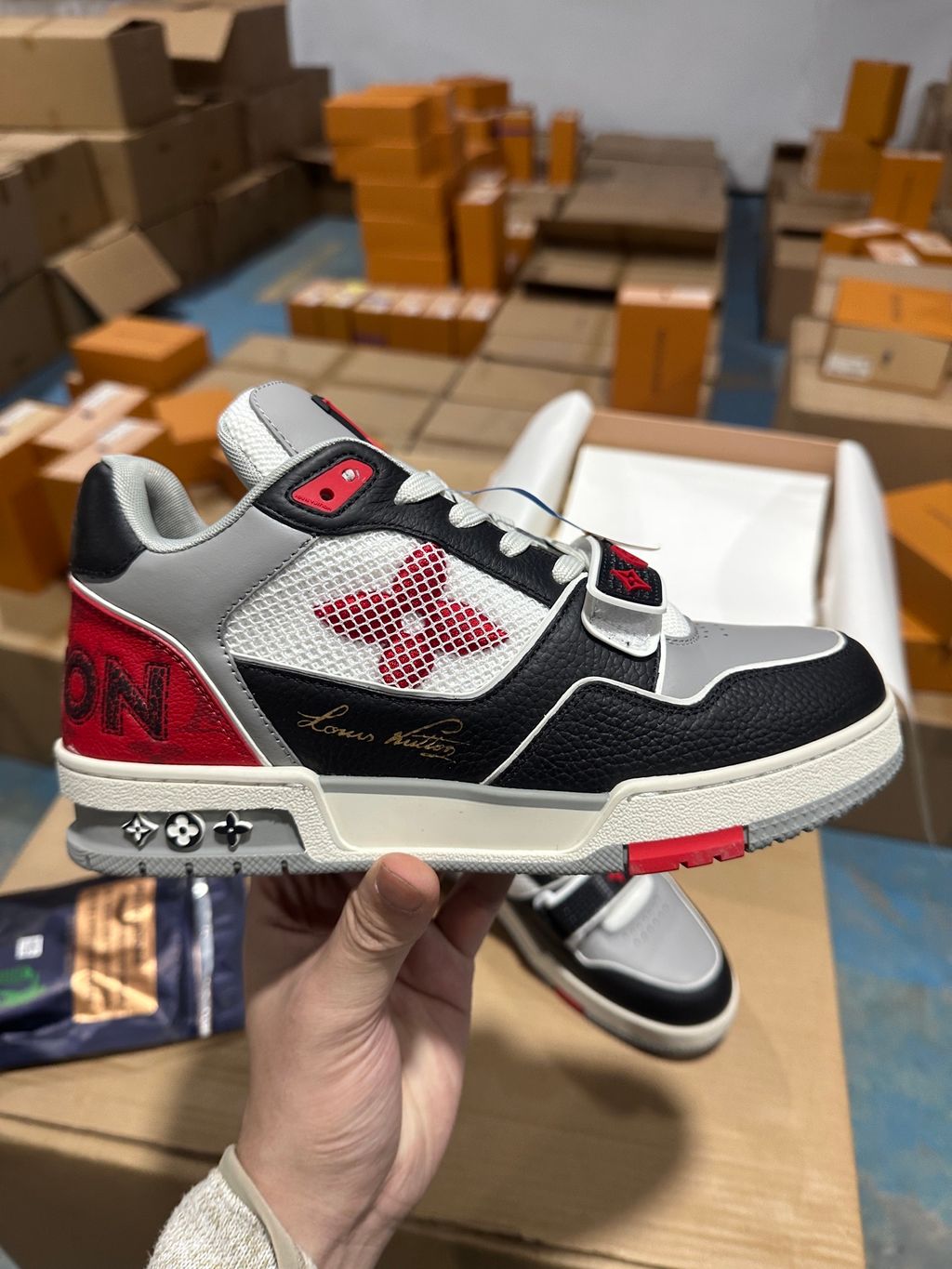 Louis Vuitton LV Trainer Mid sneaker in black, grey, and red premium calf leather, featuring a branded velcro strap across the forefoot, SKU 1AC4ZU.