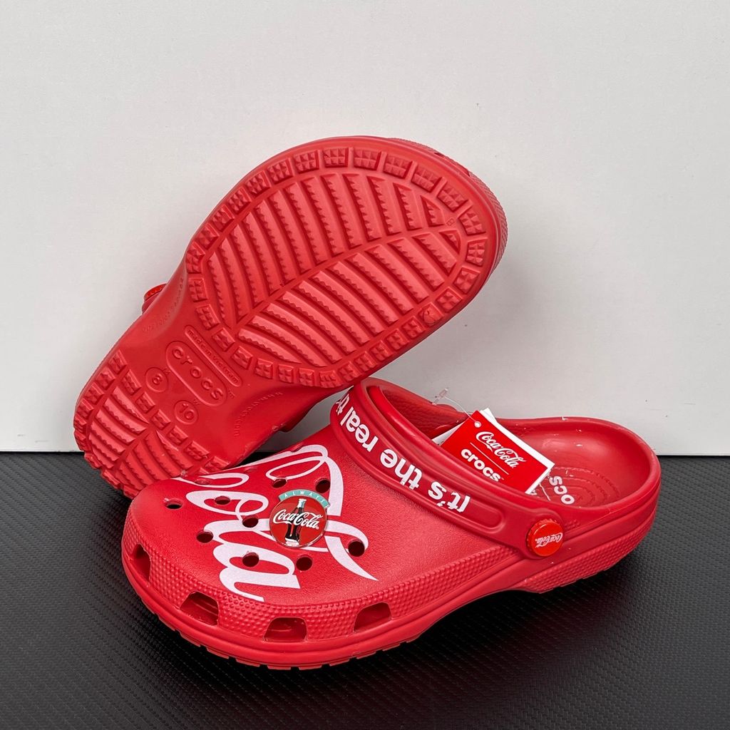 Side profile of the red Crocs x Coca-Cola Classic Clog featuring a Polar Bear Jibbitz charm, a white Coca-Cola script graphic, and red Coca-Cola logo rivets..jpg