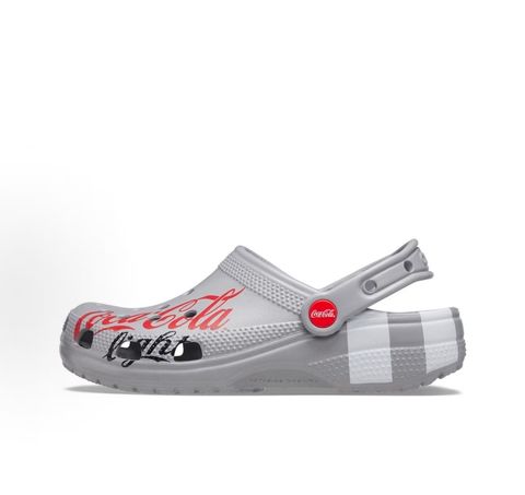 Side profile of the metallic silver Crocs x Diet Coke Classic Clog featuring a large red Coke script graphic on the toe box, a custom Diet Coke hardware rivet, and the retro slogan printed on the pivoting heel strap.