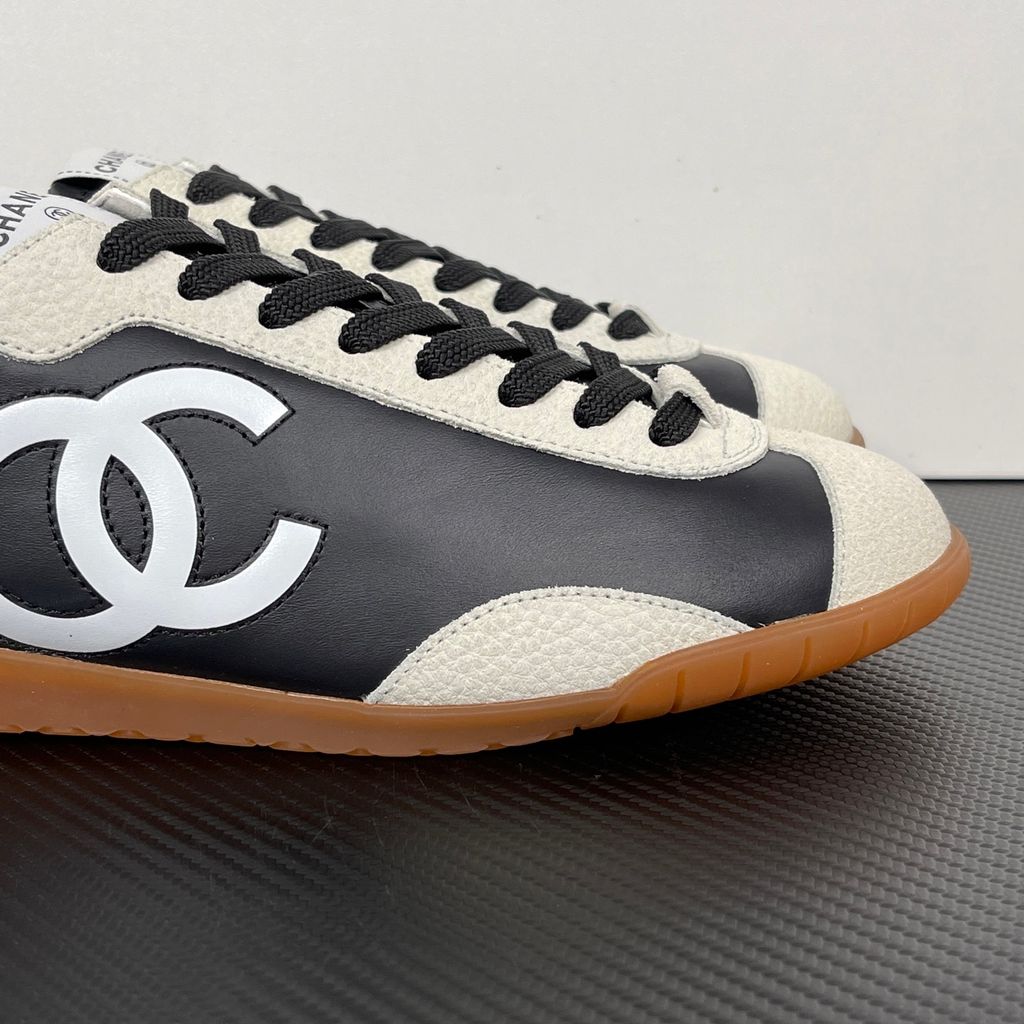 CHANEL 26P low-top sneaker in black smooth calfskin and light grey suede overlays, featuring a prominent white interlocking CC logo on the side panel and a vintage gum rubber sole, SKU G47126.