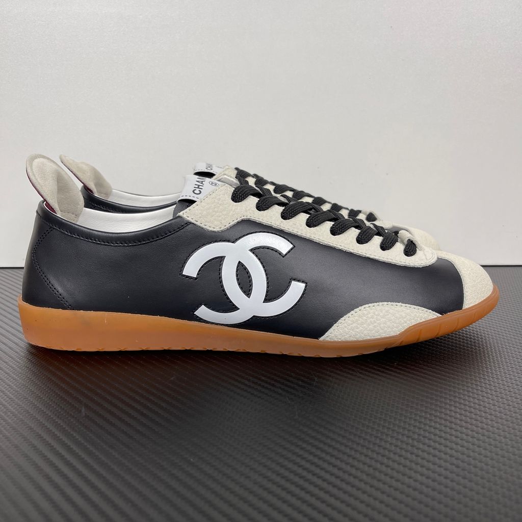 CHANEL 26P low-top sneaker in black smooth calfskin and light grey suede overlays, featuring a prominent white interlocking CC logo on the side panel and a vintage gum rubber sole, SKU G47126.