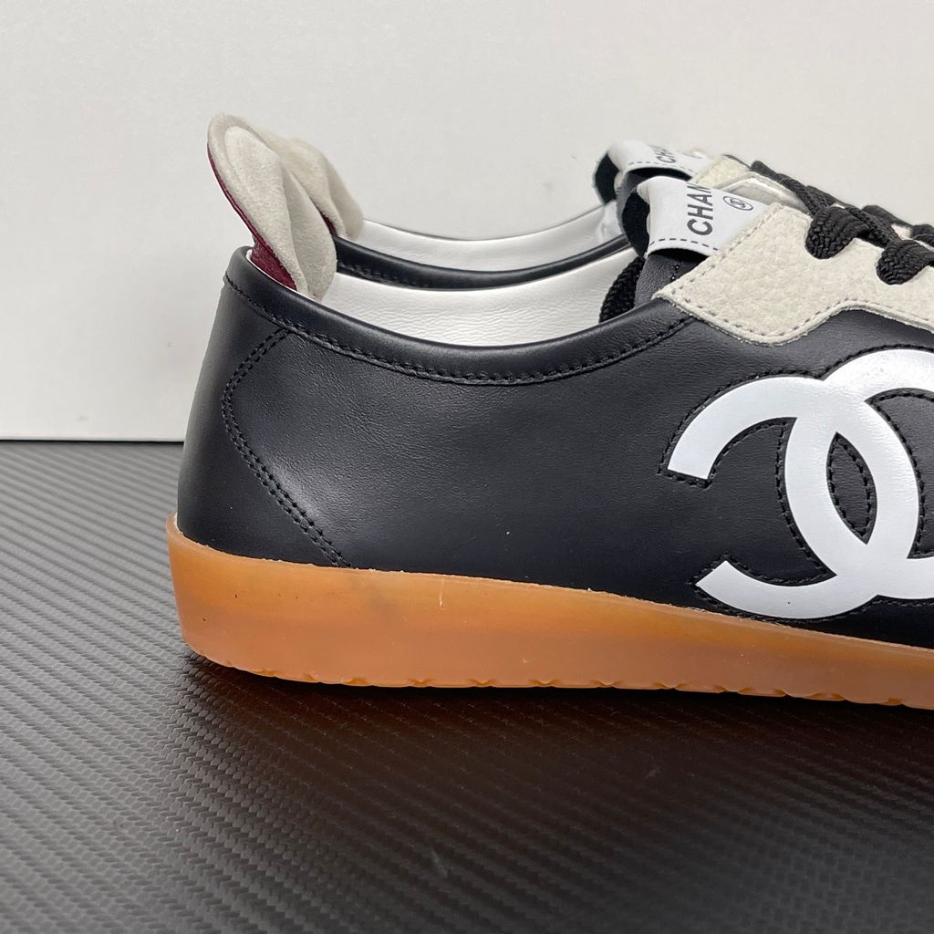 CHANEL 26P low-top sneaker in black smooth calfskin and light grey suede overlays, featuring a prominent white interlocking CC logo on the side panel and a vintage gum rubber sole, SKU G47126.