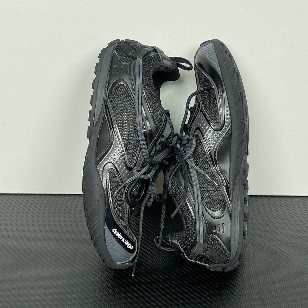 Balenciaga Radar low-profile sneaker in all black, featuring breathable mesh panels, sleek synthetic overlays, a thin driving-style sole, and the classic white Balenciaga logo on the toe edge, SKU 865704WSTE1011.
