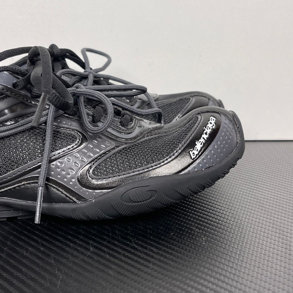 Balenciaga Radar low-profile sneaker in all black, featuring breathable mesh panels, sleek synthetic overlays, a thin driving-style sole, and the classic white Balenciaga logo on the toe edge, SKU 865704WSTE1011.