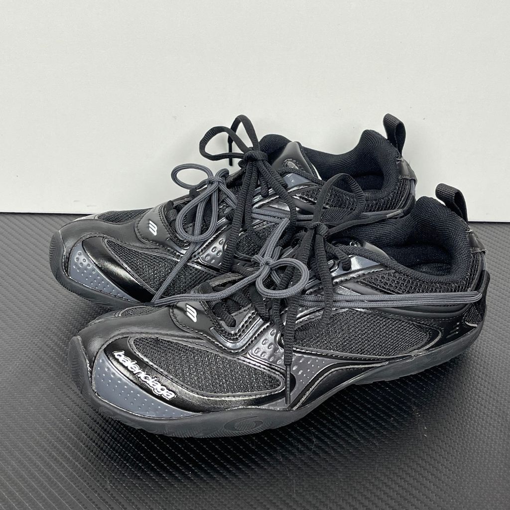 Balenciaga Radar low-profile sneaker in all black, featuring breathable mesh panels, sleek synthetic overlays, a thin driving-style sole, and the classic white Balenciaga logo on the toe edge, SKU 865704WSTE1011.