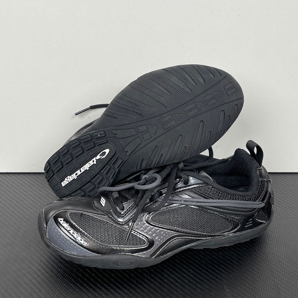 Balenciaga Radar low-profile sneaker in all black, featuring breathable mesh panels, sleek synthetic overlays, a thin driving-style sole, and the classic white Balenciaga logo on the toe edge, SKU 865704WSTE1011.
