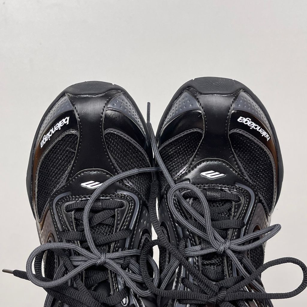 Balenciaga Radar low-profile sneaker in all black, featuring breathable mesh panels, sleek synthetic overlays, a thin driving-style sole, and the classic white Balenciaga logo on the toe edge, SKU 865704WSTE1011.
