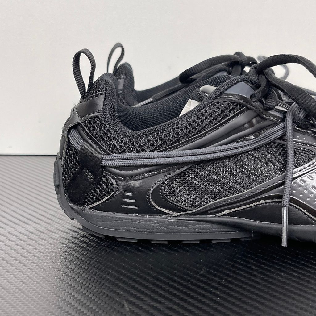 Balenciaga Radar low-profile sneaker in all black, featuring breathable mesh panels, sleek synthetic overlays, a thin driving-style sole, and the classic white Balenciaga logo on the toe edge, SKU 865704WSTE1011.