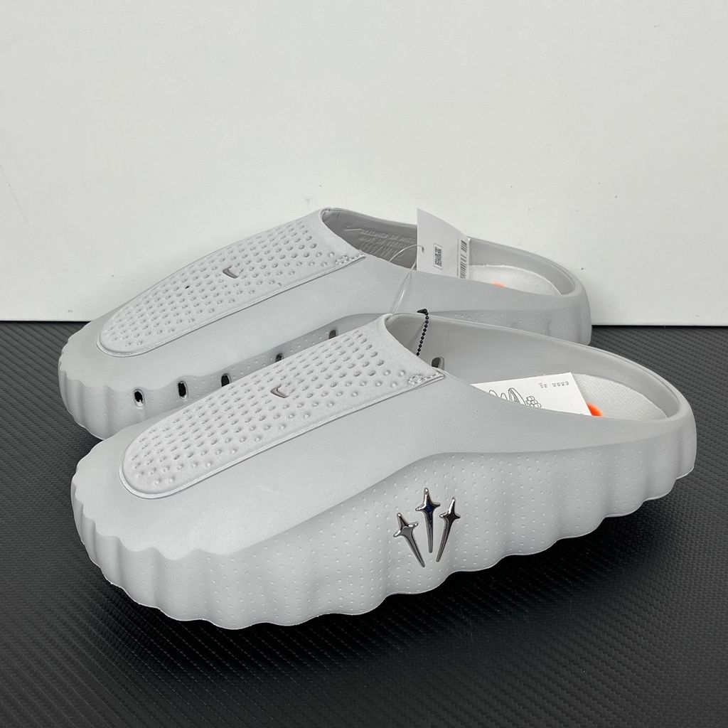 Nike x NOCTA Mind 001 premium lifestyle slide in a monochromatic light grey, featuring a tactical, tech-wear inspired molded upper and subtle NOCTA branding.