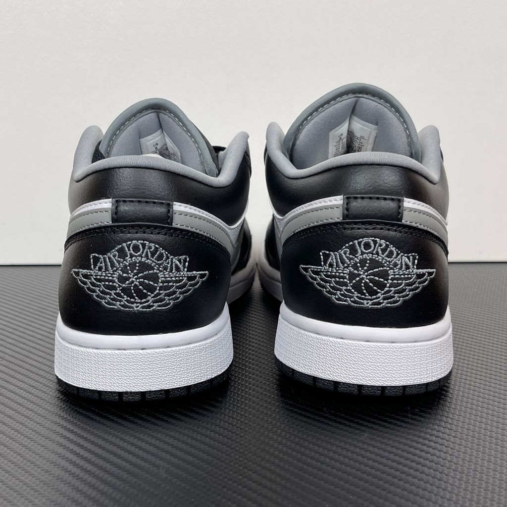 Air Jordan 1 Low lifestyle sneaker featuring a crisp white leather base, black leather overlays, and a neutral grey Swoosh and outsole, SKU 553558-040.