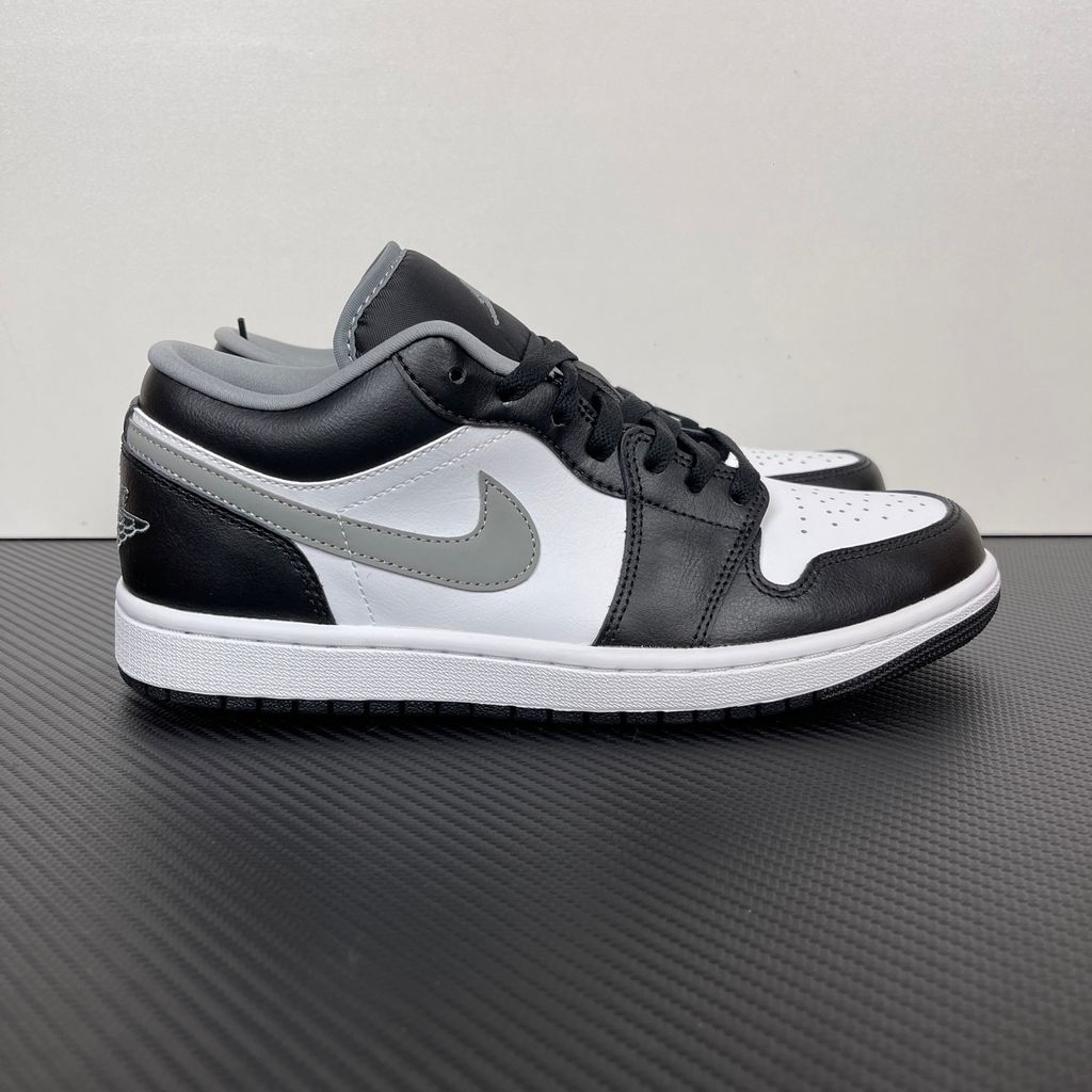 Air Jordan 1 Low lifestyle sneaker featuring a crisp white leather base, black leather overlays, and a neutral grey Swoosh and outsole, SKU 553558-040.