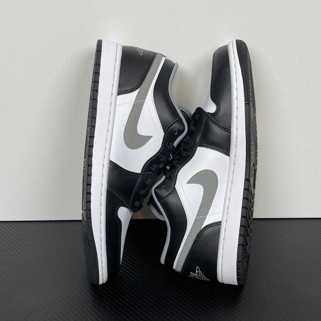 Air Jordan 1 Low lifestyle sneaker featuring a crisp white leather base, black leather overlays, and a neutral grey Swoosh and outsole, SKU 553558-040.