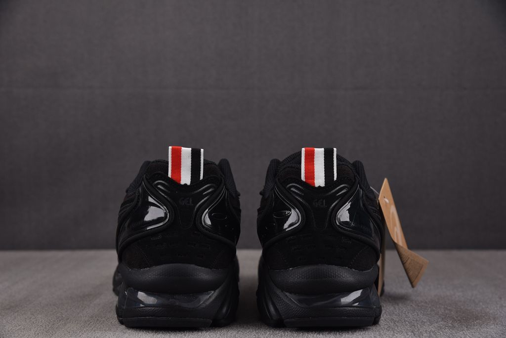 ASICS Gel-Kayano 14 x Thom Browne luxury performance sneaker in a monochromatic black colorway, featuring premium leather and mesh construction, co-branded detailing, and metallic accents, SKU 1203B110-001.