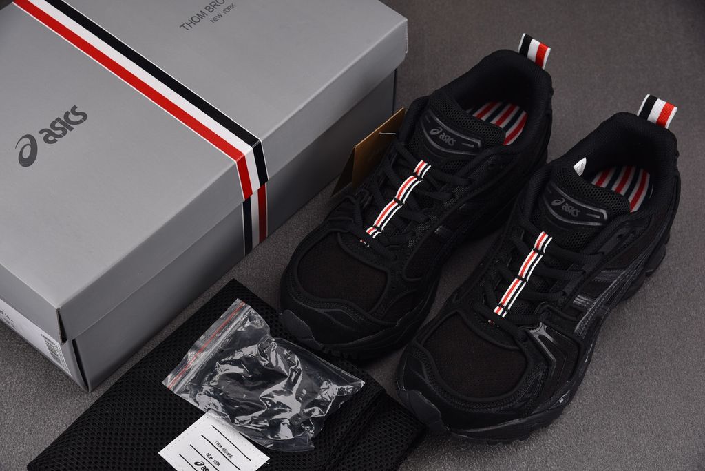 ASICS Gel-Kayano 14 x Thom Browne luxury performance sneaker in a monochromatic black colorway, featuring premium leather and mesh construction, co-branded detailing, and metallic accents, SKU 1203B110-001.