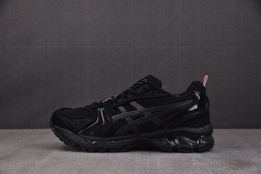 ASICS Gel-Kayano 14 x Thom Browne luxury performance sneaker in a monochromatic black colorway, featuring premium leather and mesh construction, co-branded detailing, and metallic accents, SKU 1203B110-001.