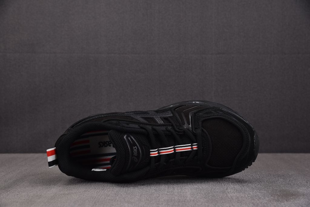 ASICS Gel-Kayano 14 x Thom Browne luxury performance sneaker in a monochromatic black colorway, featuring premium leather and mesh construction, co-branded detailing, and metallic accents, SKU 1203B110-001.
