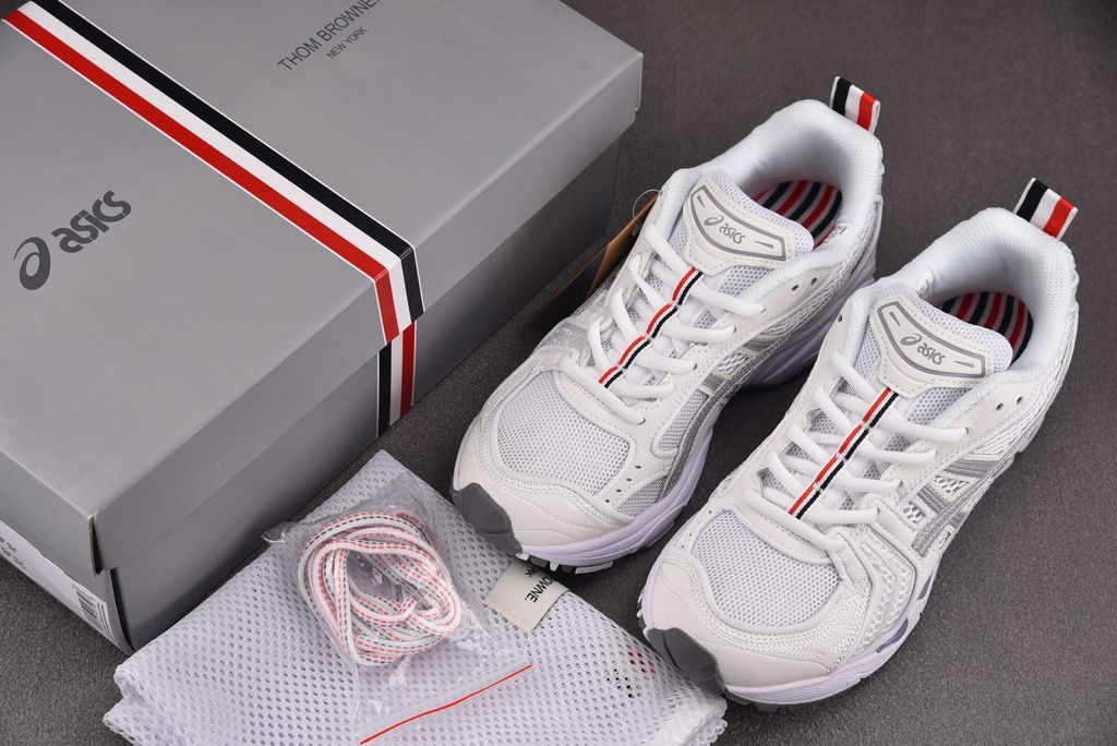 ASICS Gel-Kayano 14 x Thom Browne luxury performance sneaker in a crisp monochromatic white colorway, featuring premium leather and mesh construction, co-branded detailing, and metallic accents, SKU 1203B291-100.