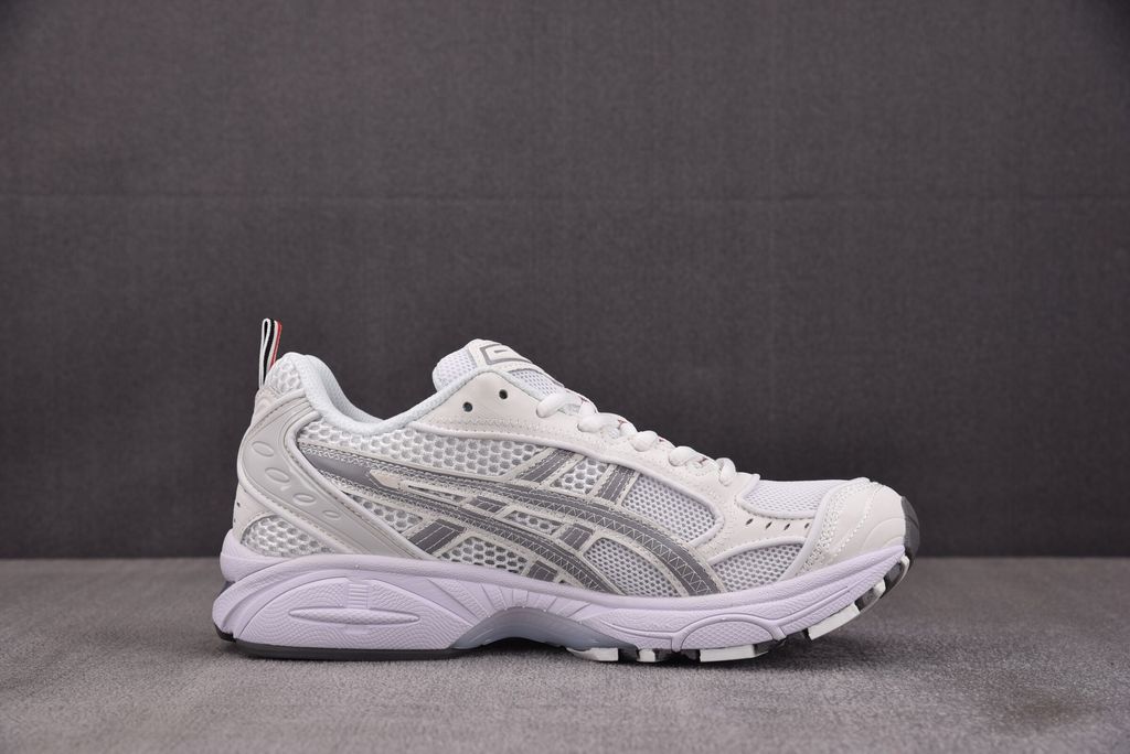 ASICS Gel-Kayano 14 x Thom Browne luxury performance sneaker in a crisp monochromatic white colorway, featuring premium leather and mesh construction, co-branded detailing, and metallic accents, SKU 1203B291-100.