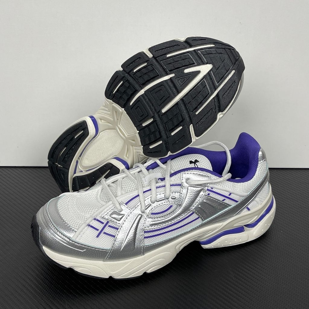 Under Armour UA Sola retro tech-runner side profile, featuring a white breathable mesh upper, dynamic metallic silver synthetic overlays, and vibrant purple accents on the midsole and collar, SKU 6005284-103.