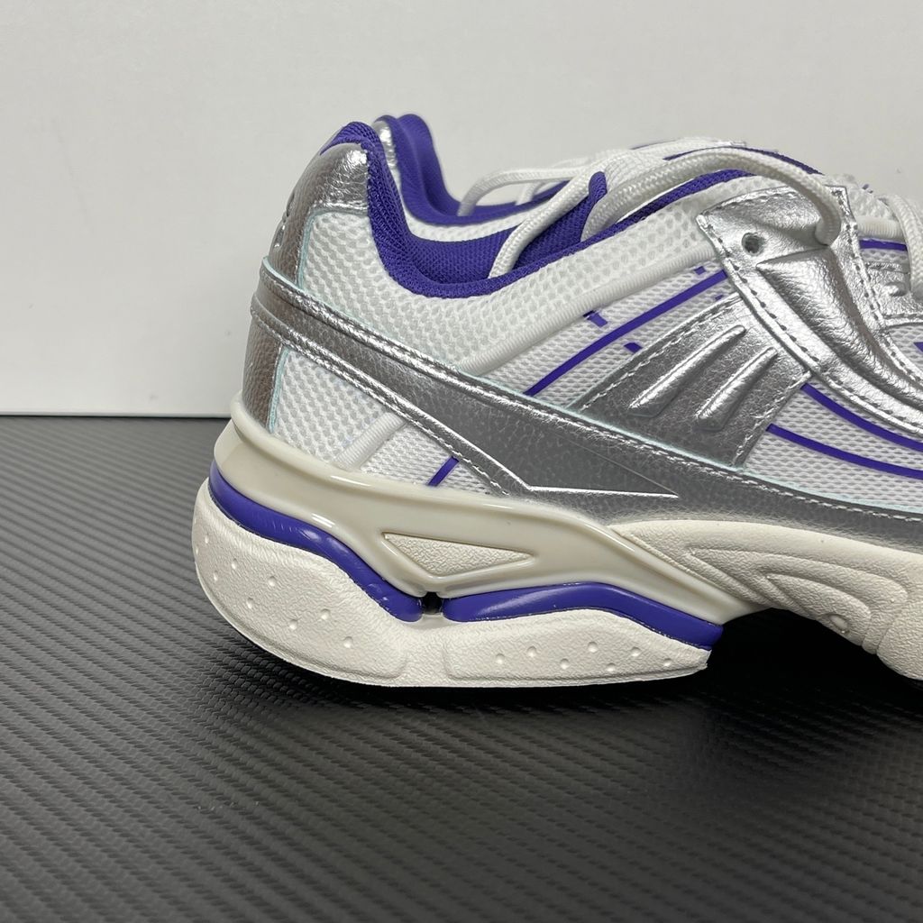 Under Armour UA Sola retro tech-runner side profile, featuring a white breathable mesh upper, dynamic metallic silver synthetic overlays, and vibrant purple accents on the midsole and collar, SKU 6005284-103.