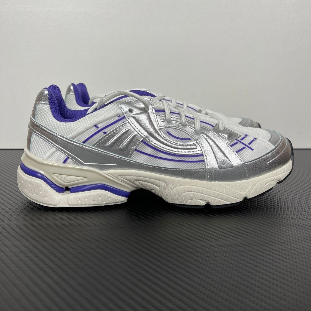 Under Armour UA Sola retro tech-runner side profile, featuring a white breathable mesh upper, dynamic metallic silver synthetic overlays, and vibrant purple accents on the midsole and collar, SKU 6005284-103.
