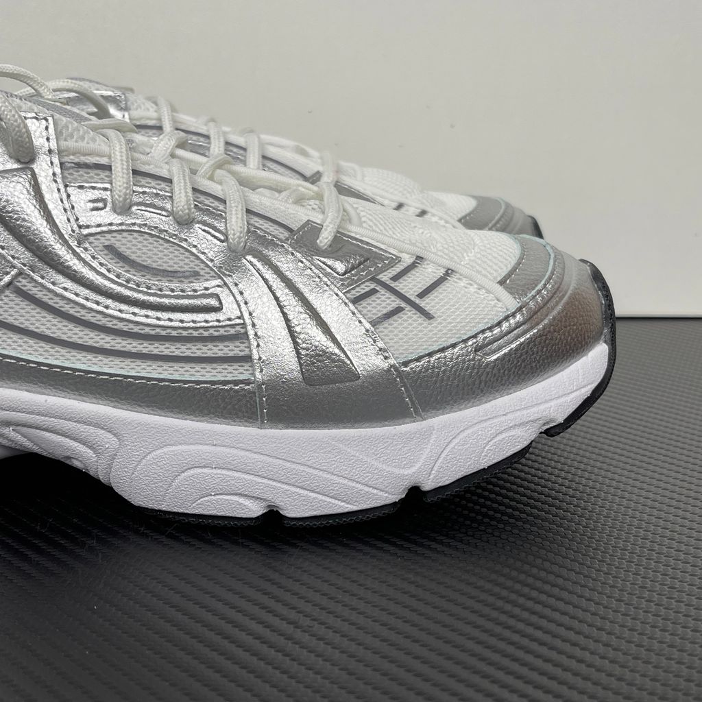 Under Armour UA Sola retro tech-runner side profile, featuring a clean white breathable mesh upper, dynamic metallic silver synthetic overlays, and a chunky white midsole, SKU 6005284-100.