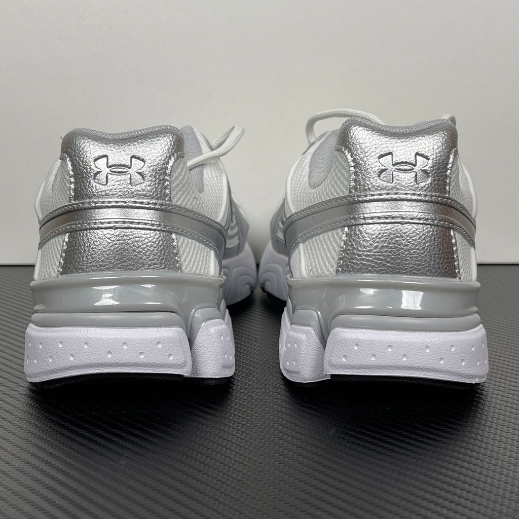 Under Armour UA Sola retro tech-runner side profile, featuring a clean white breathable mesh upper, dynamic metallic silver synthetic overlays, and a chunky white midsole, SKU 6005284-100.