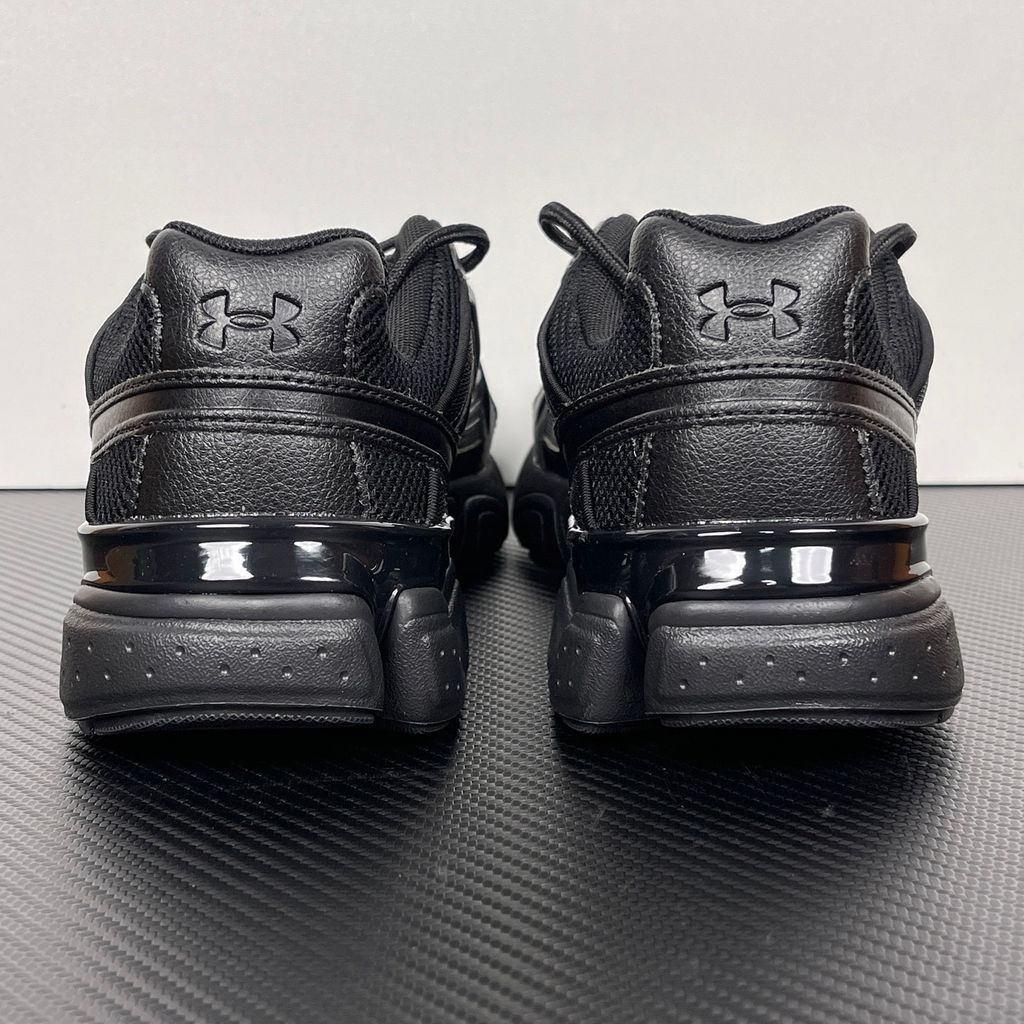 Under Armour UA Sola retro tech-runner side profile, featuring a clean triple black breathable mesh upper, dynamic tonal synthetic overlays, and a chunky black midsole, SKU 6005284-003.