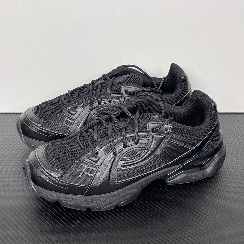 Under Armour UA Sola retro tech-runner side profile, featuring a clean triple black breathable mesh upper, dynamic tonal synthetic overlays, and a chunky black midsole, SKU 6005284-003.