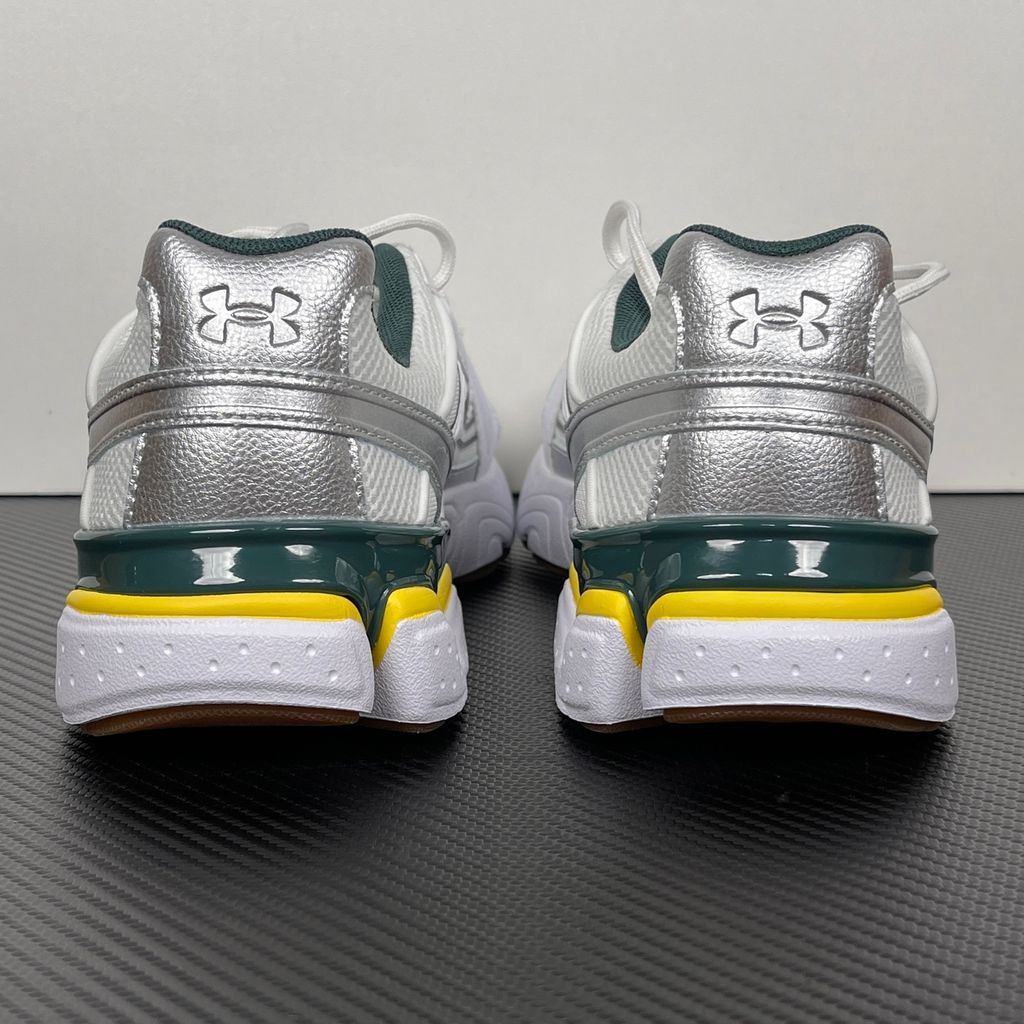 Under Armour UA Sola retro tech-runner side profile, featuring a clean white breathable mesh upper, dynamic metallic silver overlays, dark green collar lining, bright yellow midsole accents, and a classic gum rubber outsole, SKU 6005284-104.