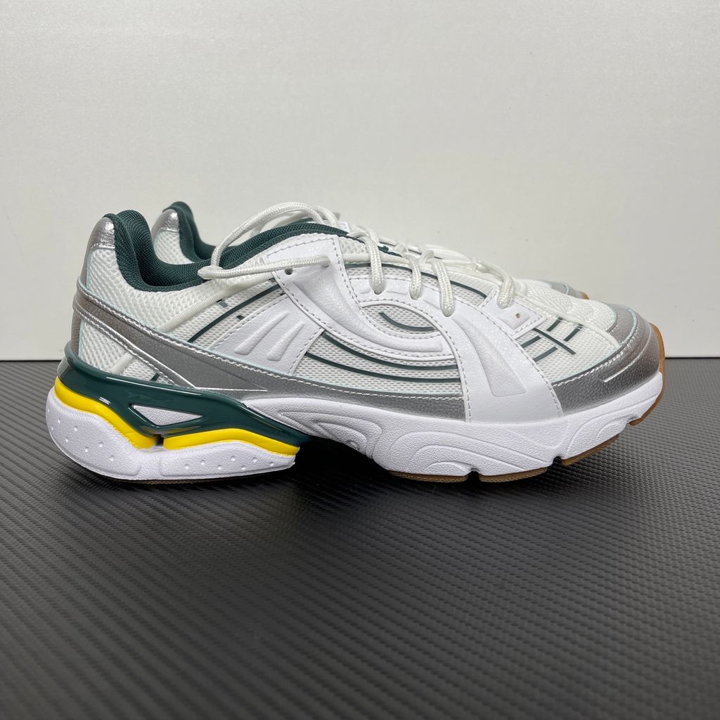 Under Armour UA Sola retro tech-runner side profile, featuring a clean white breathable mesh upper, dynamic metallic silver overlays, dark green collar lining, bright yellow midsole accents, and a classic gum rubber outsole, SKU 6005284-104.