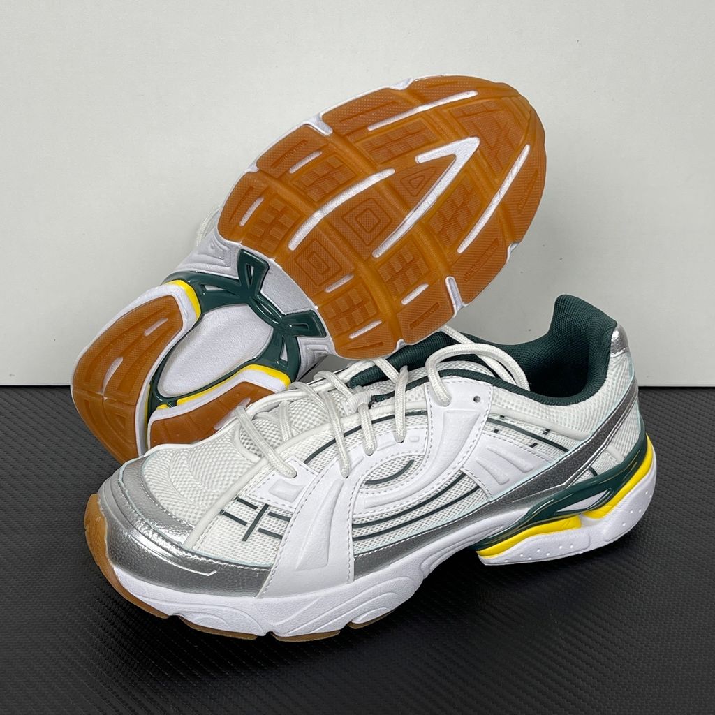Under Armour UA Sola retro tech-runner side profile, featuring a clean white breathable mesh upper, dynamic metallic silver overlays, dark green collar lining, bright yellow midsole accents, and a classic gum rubber outsole, SKU 6005284-104.
