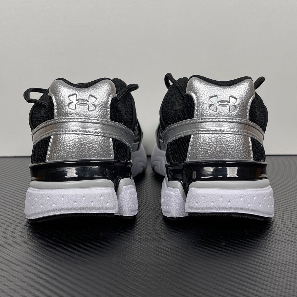 Under Armour UA Sola retro tech-runner side profile, featuring a clean black breathable mesh upper, dynamic black and metallic silver synthetic overlays, and a chunky white midsole, SKU 6005284-004.