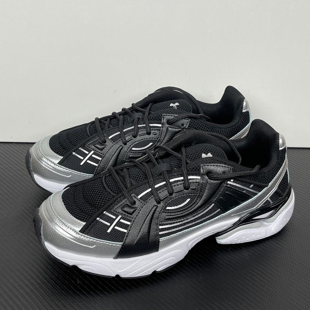 Under Armour UA Sola retro tech-runner side profile, featuring a clean black breathable mesh upper, dynamic black and metallic silver synthetic overlays, and a chunky white midsole, SKU 6005284-004.