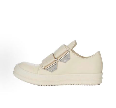 Side profile of the Rick Owens Mainline low-top sneaker in off-white leather, featuring distinctive industrial metal hardware, textured velcro strap closures, and a chunky tonal rubber sole.