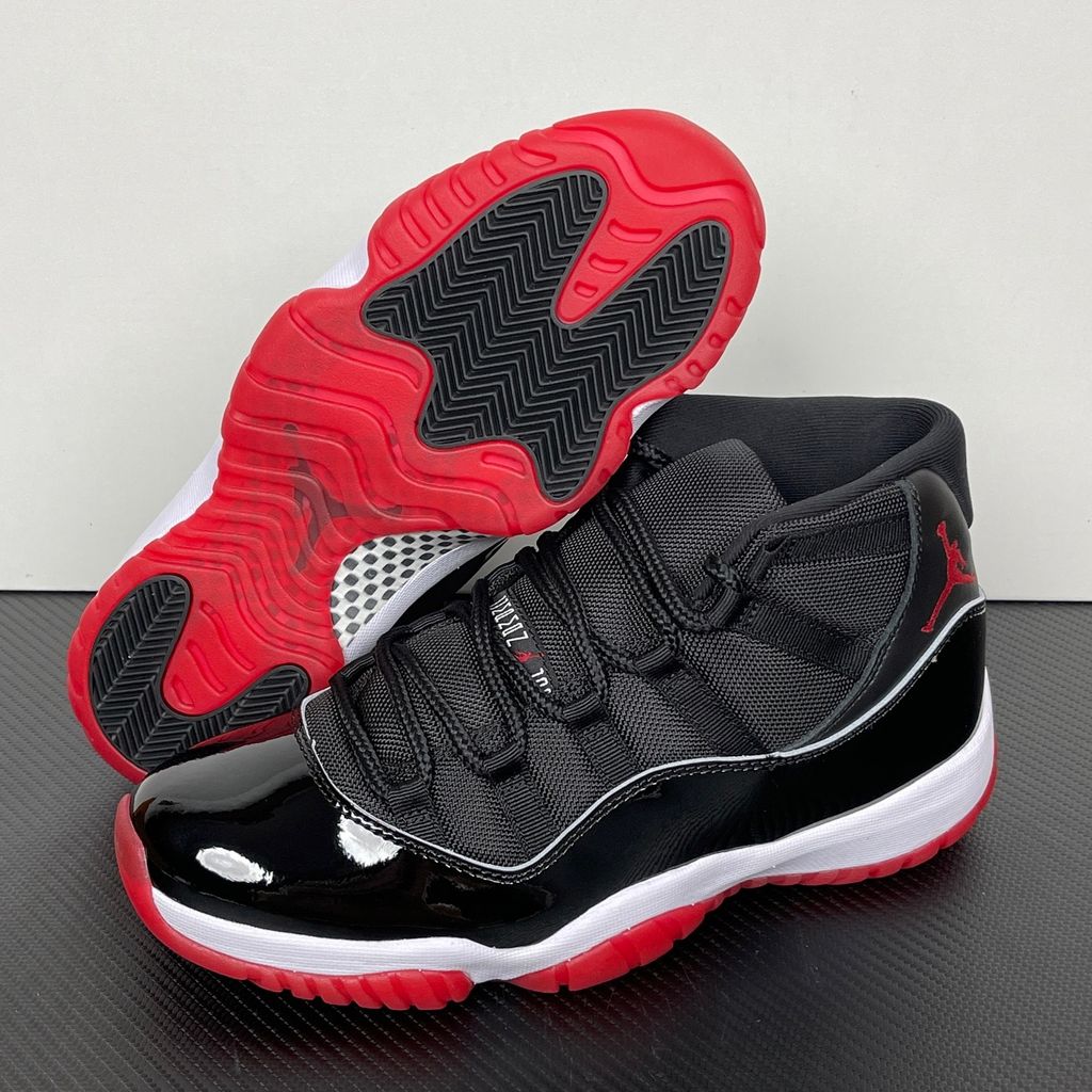 Side profile of the Air Jordan 11 Retro 'Bred' (2019), showcasing the black mesh upper, signature high-cut black patent leather mudguard, and crisp white Phylon midsole.