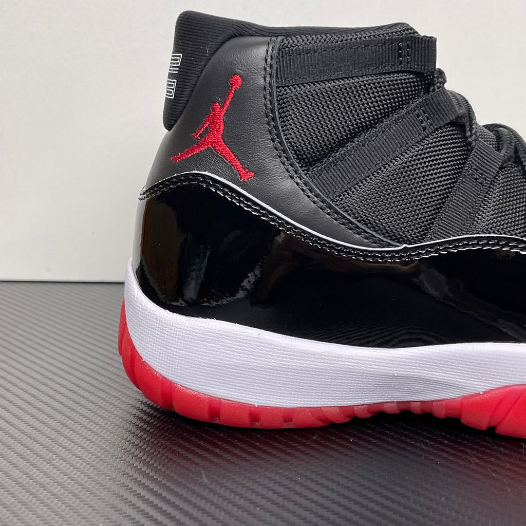 Side profile of the Air Jordan 11 Retro 'Bred' (2019), showcasing the black mesh upper, signature high-cut black patent leather mudguard, and crisp white Phylon midsole.