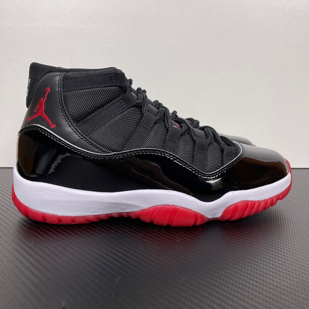 Side profile of the Air Jordan 11 Retro 'Bred' (2019), showcasing the black mesh upper, signature high-cut black patent leather mudguard, and crisp white Phylon midsole.