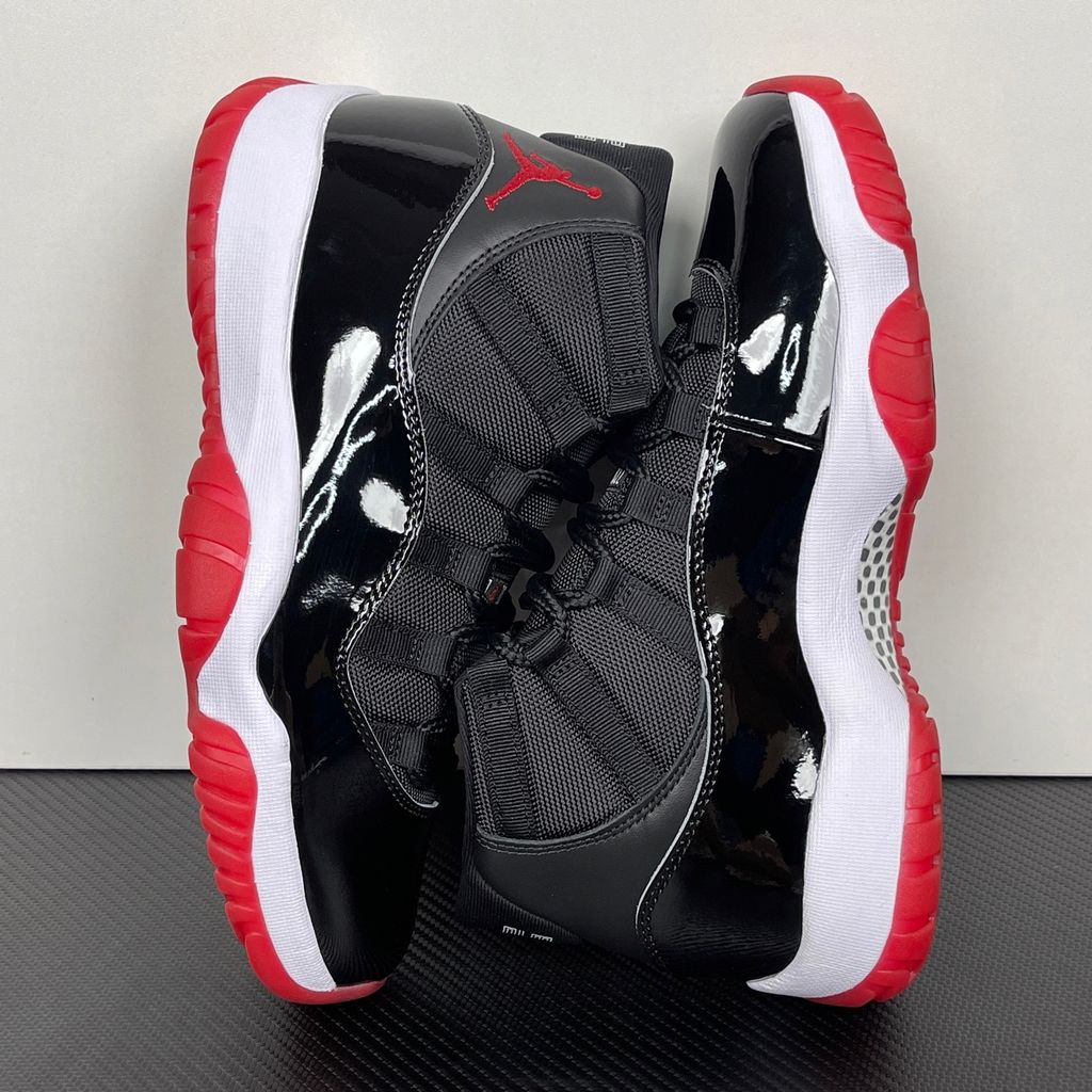 Side profile of the Air Jordan 11 Retro 'Bred' (2019), showcasing the black mesh upper, signature high-cut black patent leather mudguard, and crisp white Phylon midsole.
