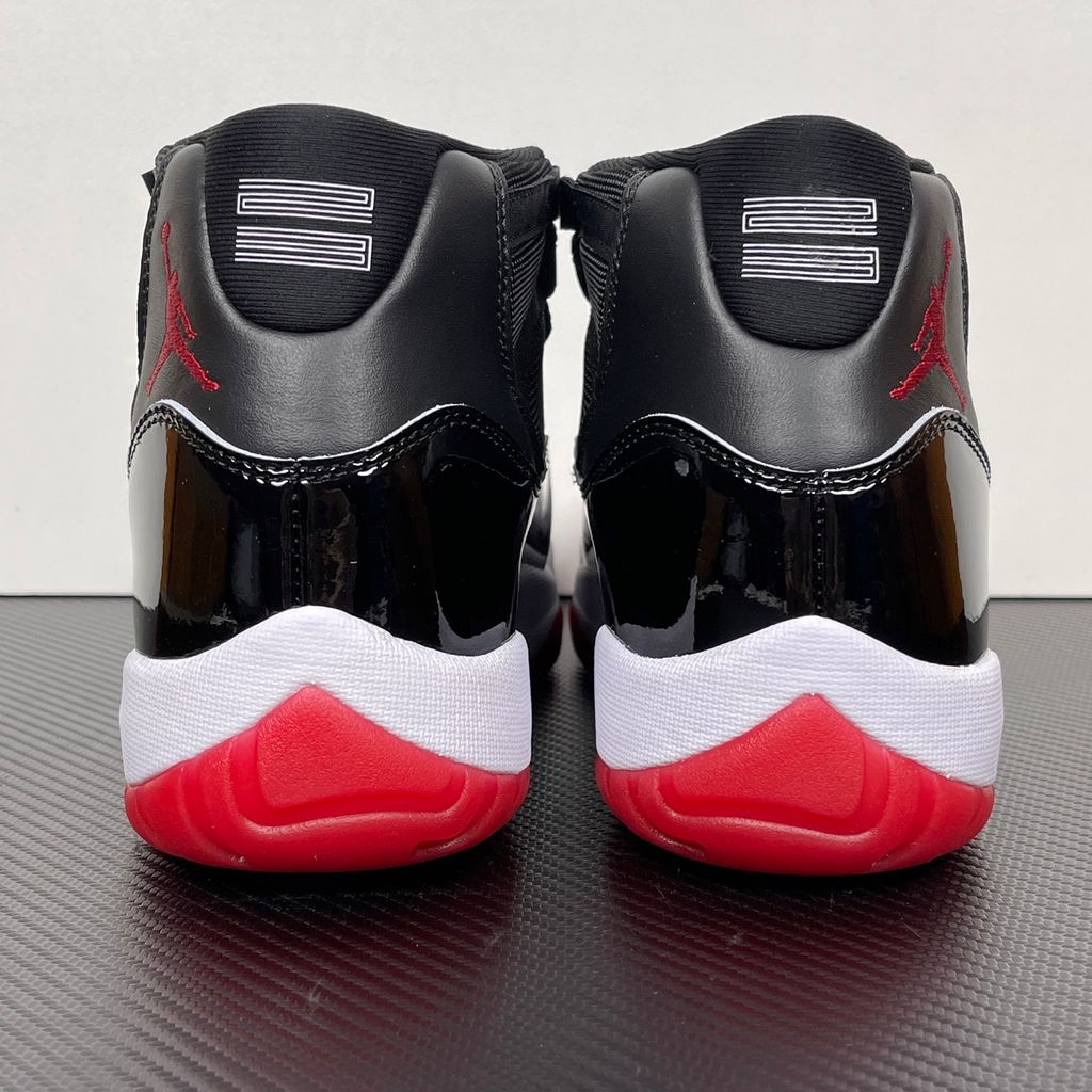 Side profile of the Air Jordan 11 Retro 'Bred' (2019), showcasing the black mesh upper, signature high-cut black patent leather mudguard, and crisp white Phylon midsole.