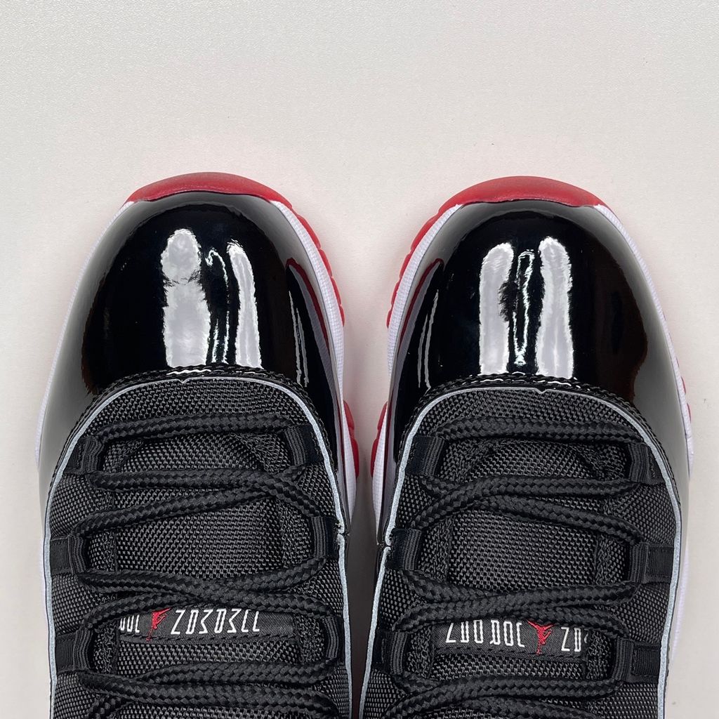Side profile of the Air Jordan 11 Retro 'Bred' (2019), showcasing the black mesh upper, signature high-cut black patent leather mudguard, and crisp white Phylon midsole.