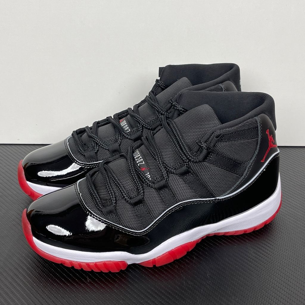 Side profile of the Air Jordan 11 Retro 'Bred' (2019), showcasing the black mesh upper, signature high-cut black patent leather mudguard, and crisp white Phylon midsole.