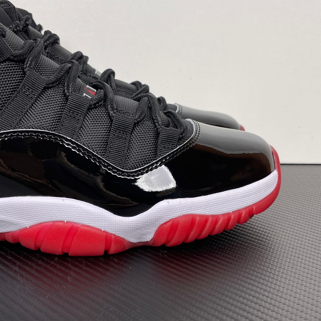 Side profile of the Air Jordan 11 Retro 'Bred' (2019), showcasing the black mesh upper, signature high-cut black patent leather mudguard, and crisp white Phylon midsole.