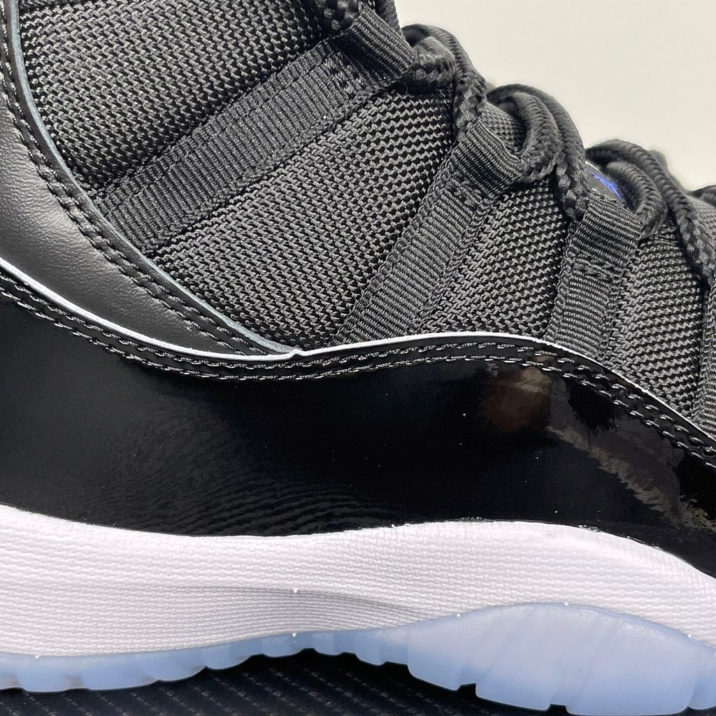 Side profile of the Air Jordan 11 Retro 'Space Jam' (2016), showcasing the black mesh upper, signature high-cut black patent leather mudguard, and crisp white Phylon midsole.