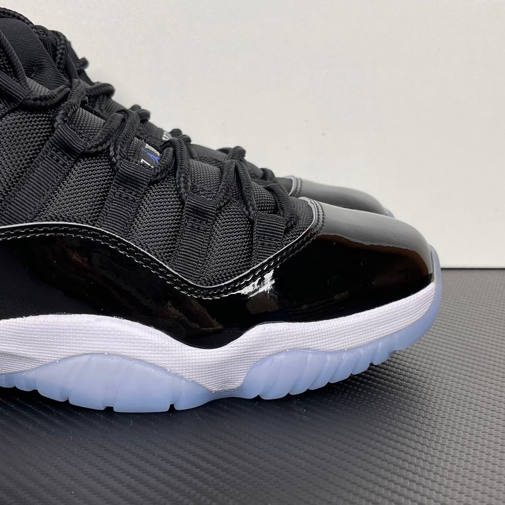 Side profile of the Air Jordan 11 Retro 'Space Jam' (2016), showcasing the black mesh upper, signature high-cut black patent leather mudguard, and crisp white Phylon midsole.