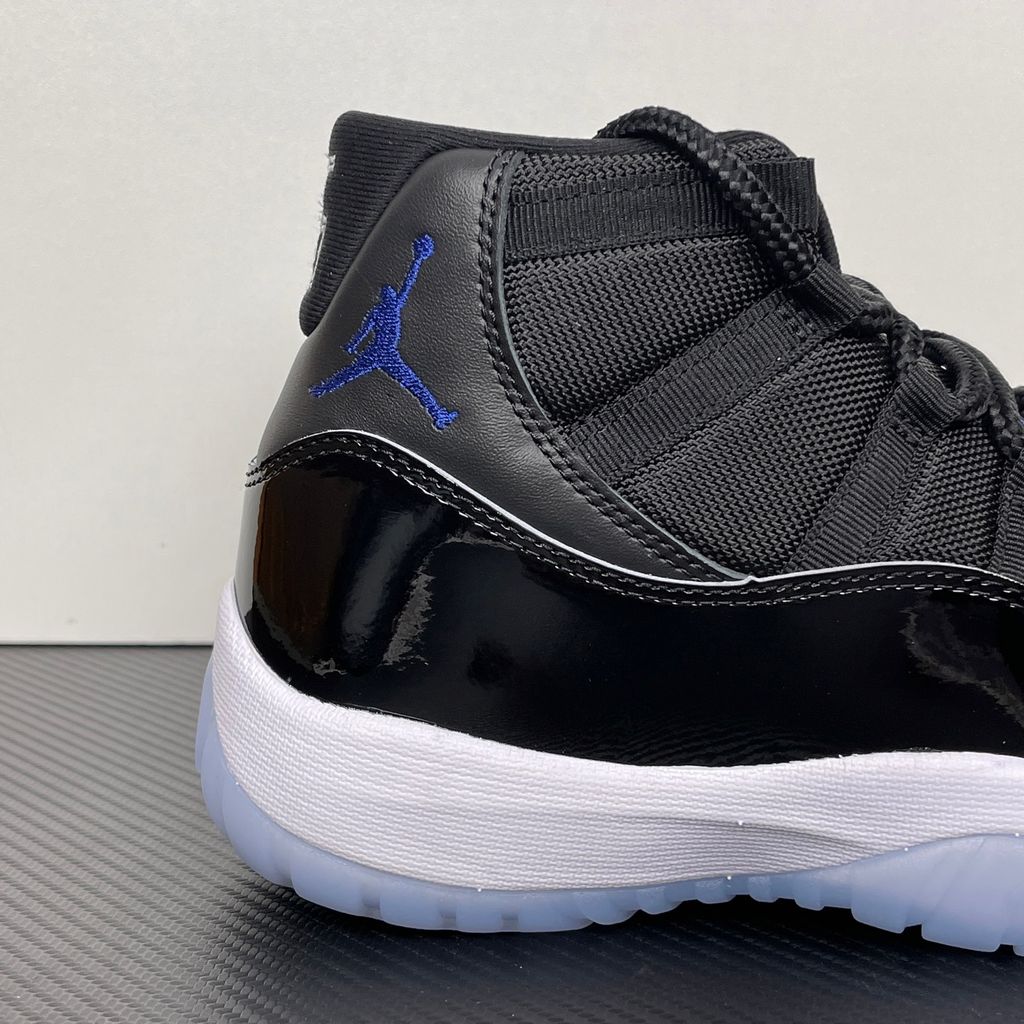 Side profile of the Air Jordan 11 Retro 'Space Jam' (2016), showcasing the black mesh upper, signature high-cut black patent leather mudguard, and crisp white Phylon midsole.